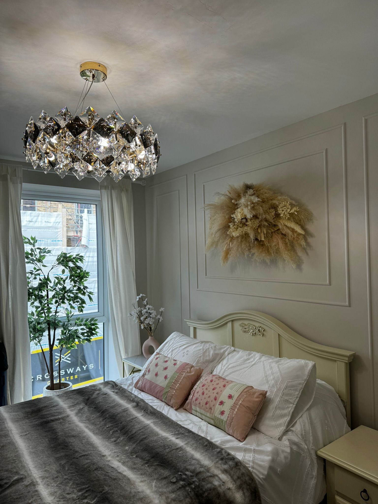 Bedroom with crystal chandelier and dried floral wall art