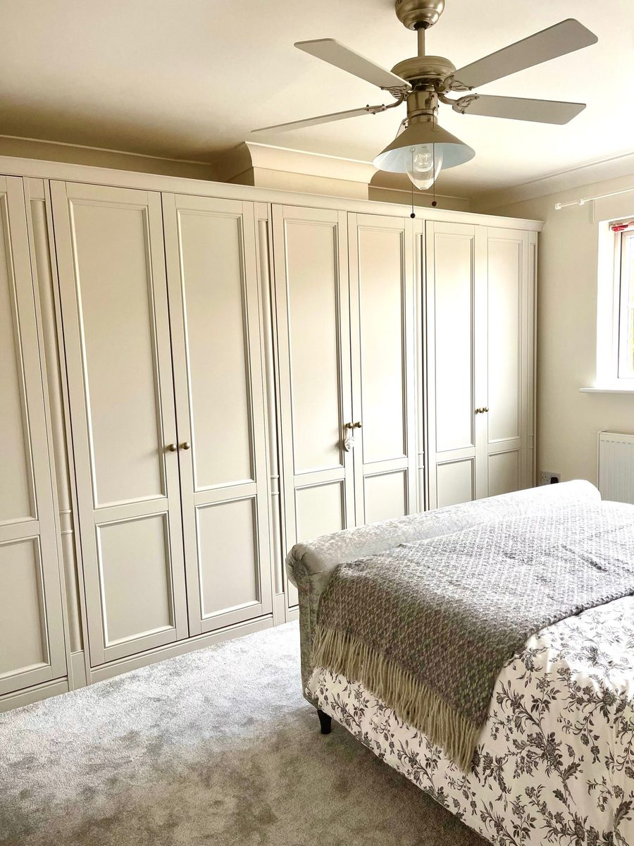 Bedroom with bespoke fitted wardrobes in warm cream with brass handles