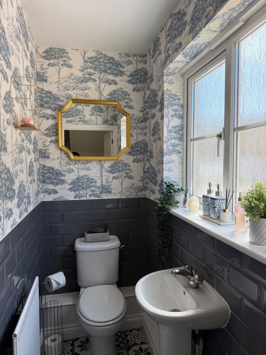 Cloakroom with toile wallpaper, navy wainscoting and gold ornate mirror