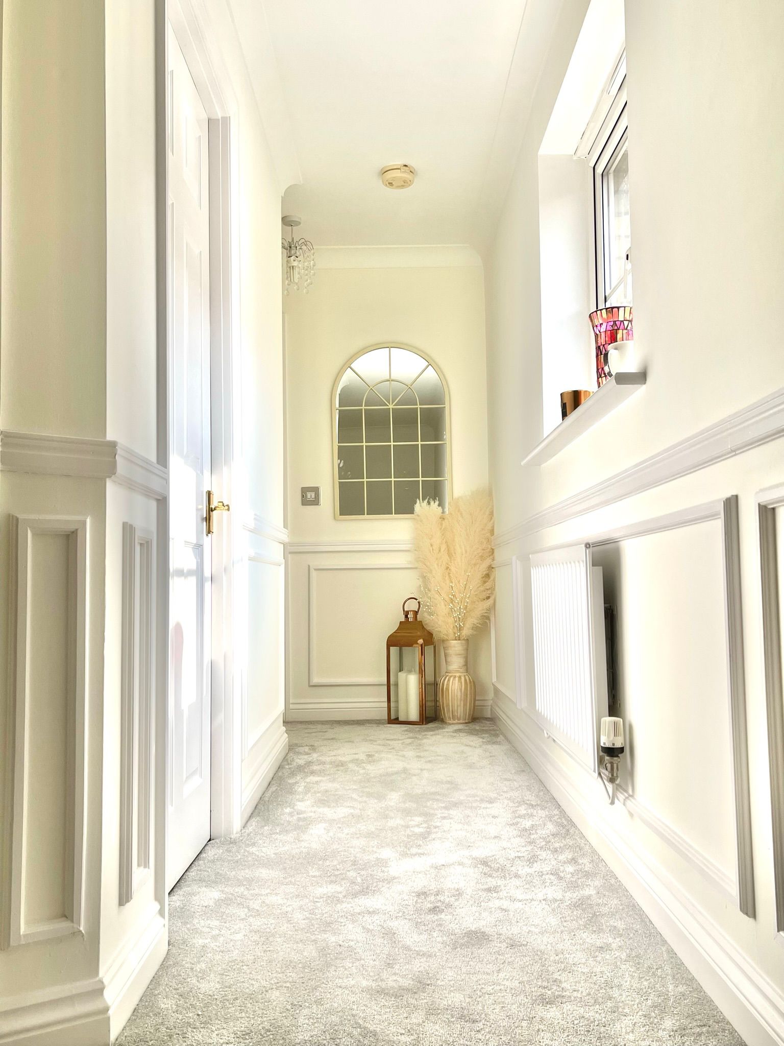 Hallway interior design by Maison Zohora — arched mirror, pampas grass, panelled walls in soft neutral tones