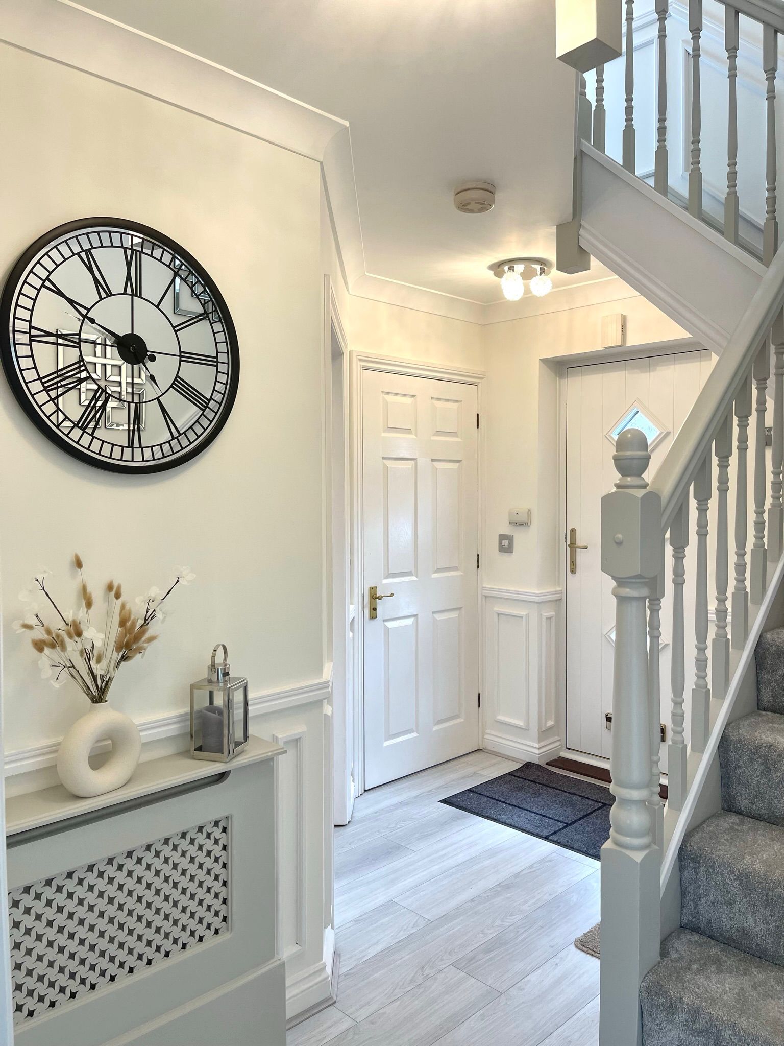 Hallway styling by Maison Zohora — console table with florals, statement clock, grey painted staircase